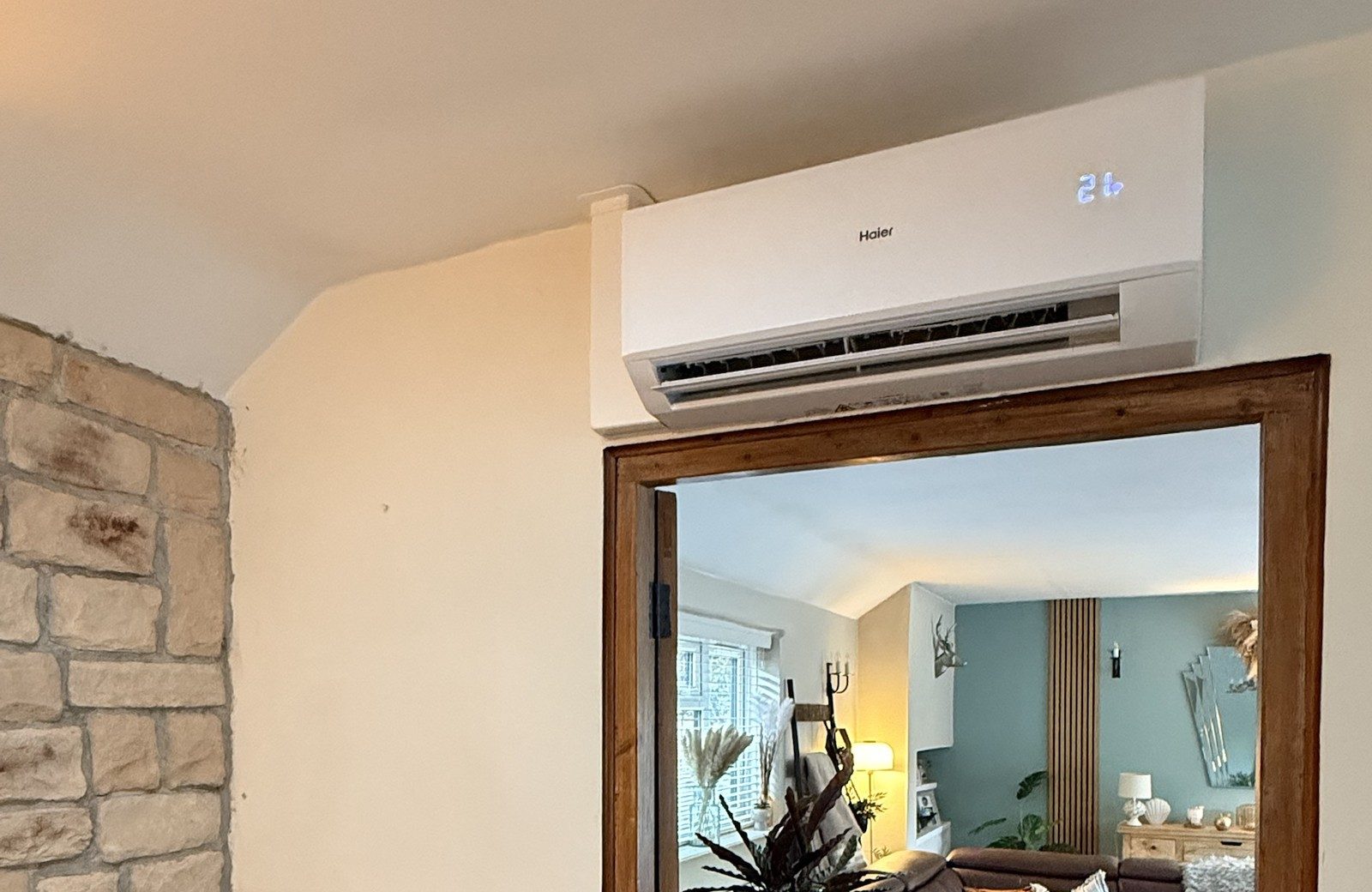 Haier wall-mounted heat pump fitted above a doorway in a cottage living room