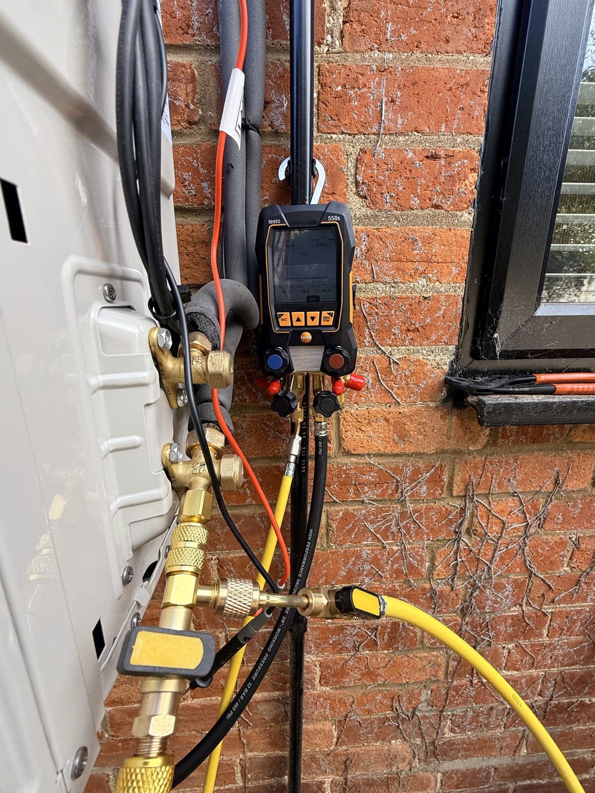 Digital refrigeration manifold gauges connected to the outdoor unit service valves