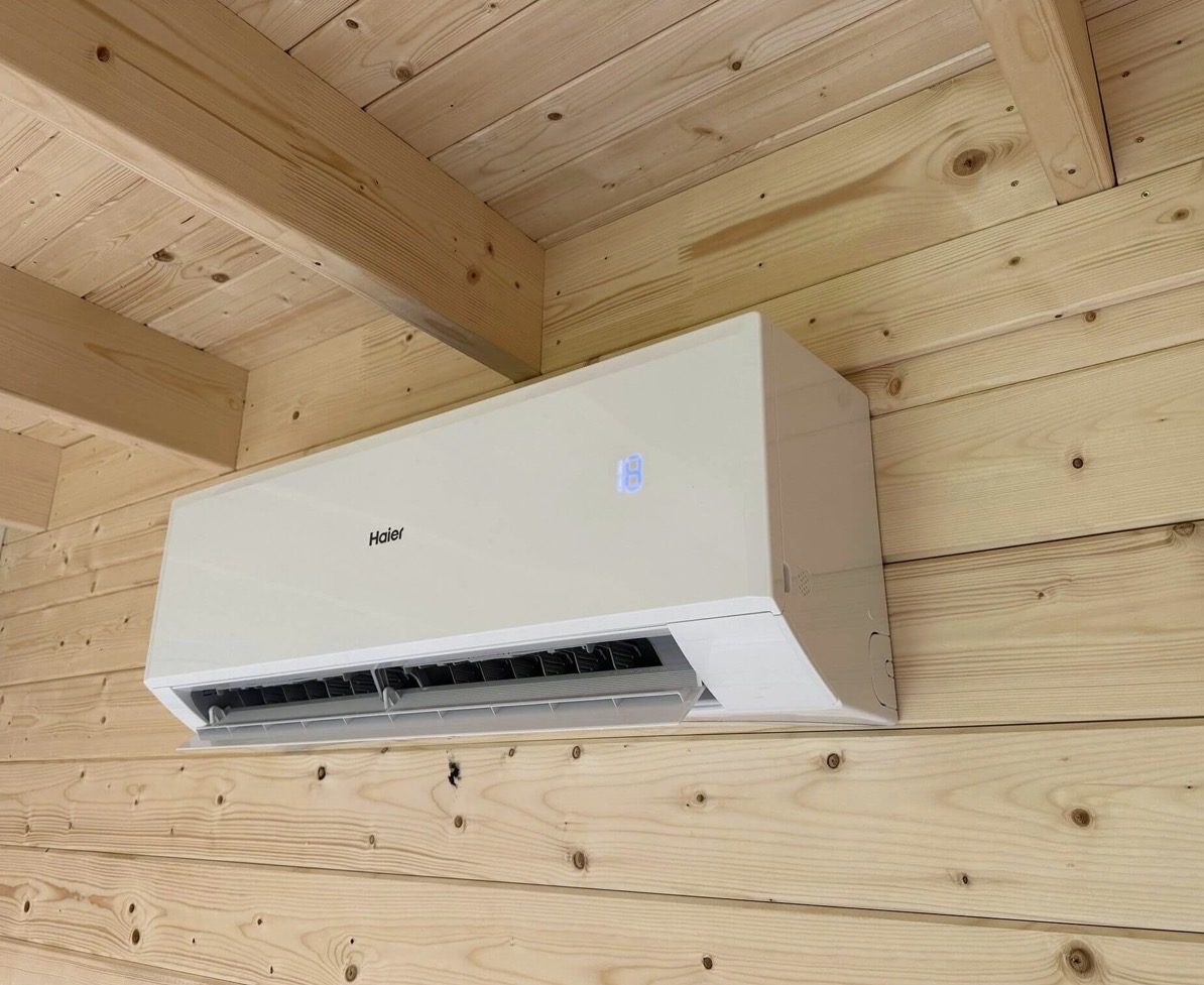 Haier wall-mounted air conditioning unit high on a pine-clad wall in an Aylesbury garden office